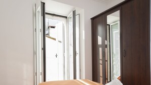 A bedroom with an open door leading outside, a bed with an orange bedspread, and a large mirror on the wall. - Los truques (Santiago de Compostela)