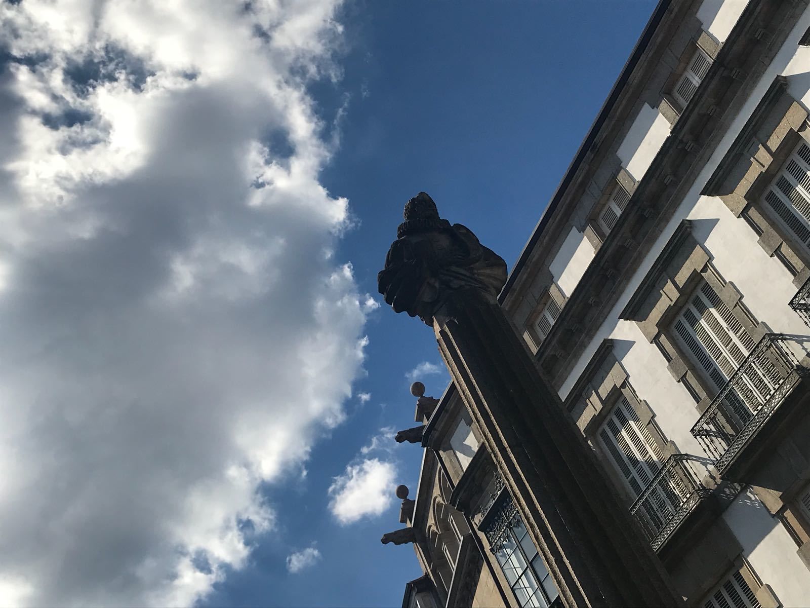 Ein Gebäude im klassischen Stil, mit einer Statue auf dem Dach und zahlreichen Fenstern.