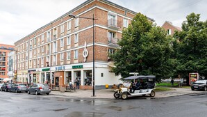 Een meerlaags gebouw met een bakstenen gevel, winkels op de begane grond en een straat ervoor.