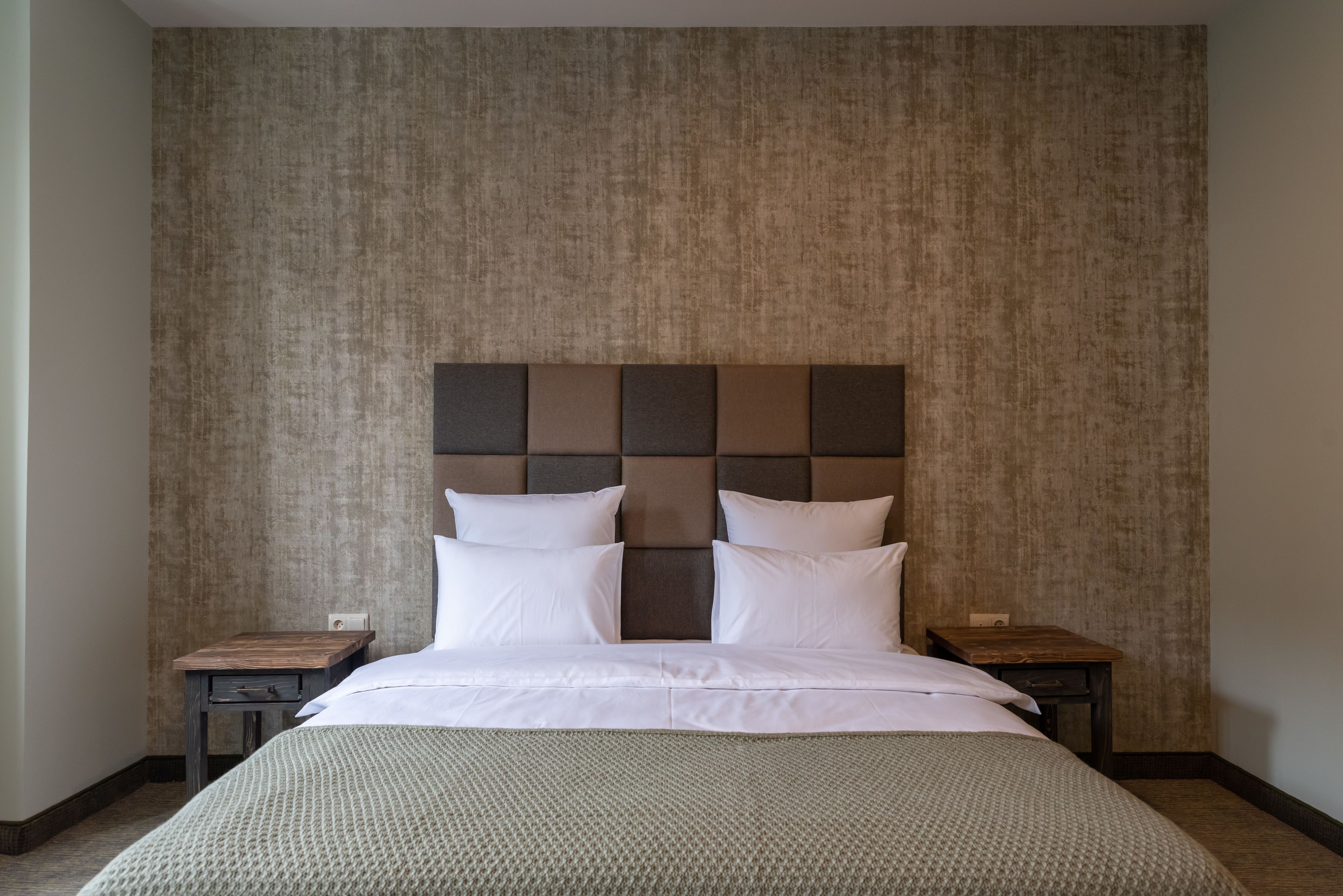 A bedroom with a large bed, a textured wall, and two nightstands.