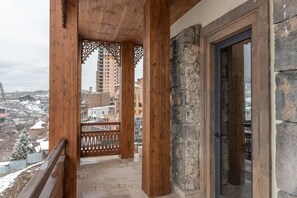 A wooden balcony with stone pillars, a metal railing, and a view of a snowy town. - Apricot Hotel Yerevan (Yerevan)