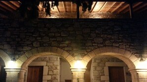 A stone archway leading to a wooden door, a staircase, and a chair in a dimly lit area. - Eski Datça Evleri Mini Hotel (Datça)