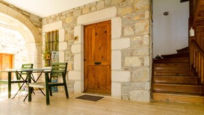 A stone-walled room with a wooden door, a table with chairs, and a staircase. - Eski Datça Evleri Mini Hotel (Datça)