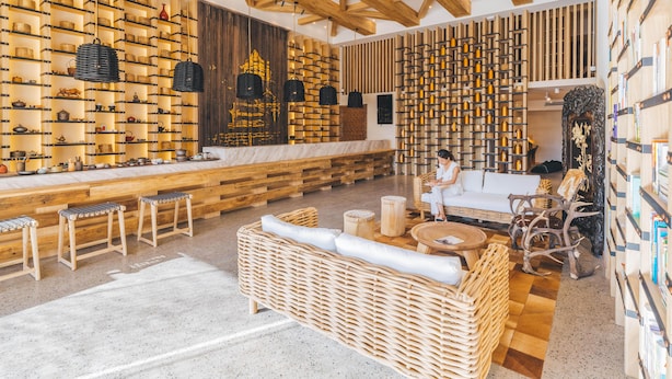 A modern interior with wooden beams, a bar area with stools, a seating area with a sofa and chairs, and shelves with bottles. - Atour Hotel Sun YatSen Mausoleum Scenic Spot Nanjing (Nanjing)