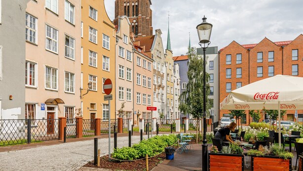 Eine Straße mit Gebäuden, einem Marktstand und einem Coca-Cola-Sonnenschirm.