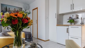 Ein modernes Wohnzimmer mit einem Glastisch, einer Blumenvase, einer Couch und einem Gemälde an der Wand.