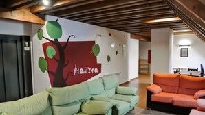 Un interior modern amb un sofà verd, un sofà taronja i un mural amb un arbre i la paraula "Haizoo".