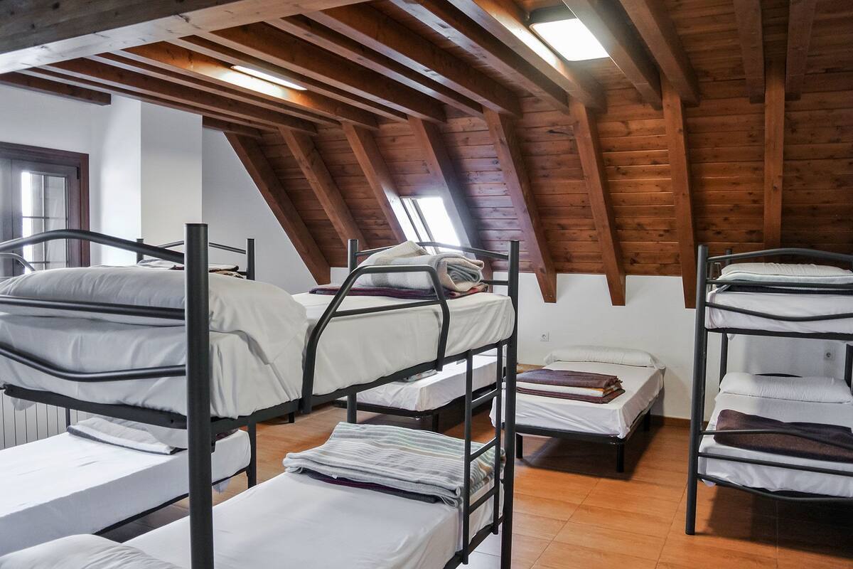 Un dormitorio con literas, vigas de madera y tragaluces.