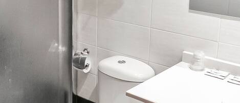 Un baño con inodoro, cabina de ducha y lavabo con espejo.