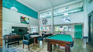 A billiards room with a pool table, chairs, and a foosball table. - Apartamento 1 quarto Summer Beach - 320 (Bombinhas)