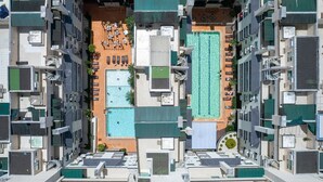 An aerial view of a residential building with multiple balconies, a rooftop pool area, and a small outdoor seating area. - Apartamento 1 quarto Summer Beach - 320 (Bombinhas)