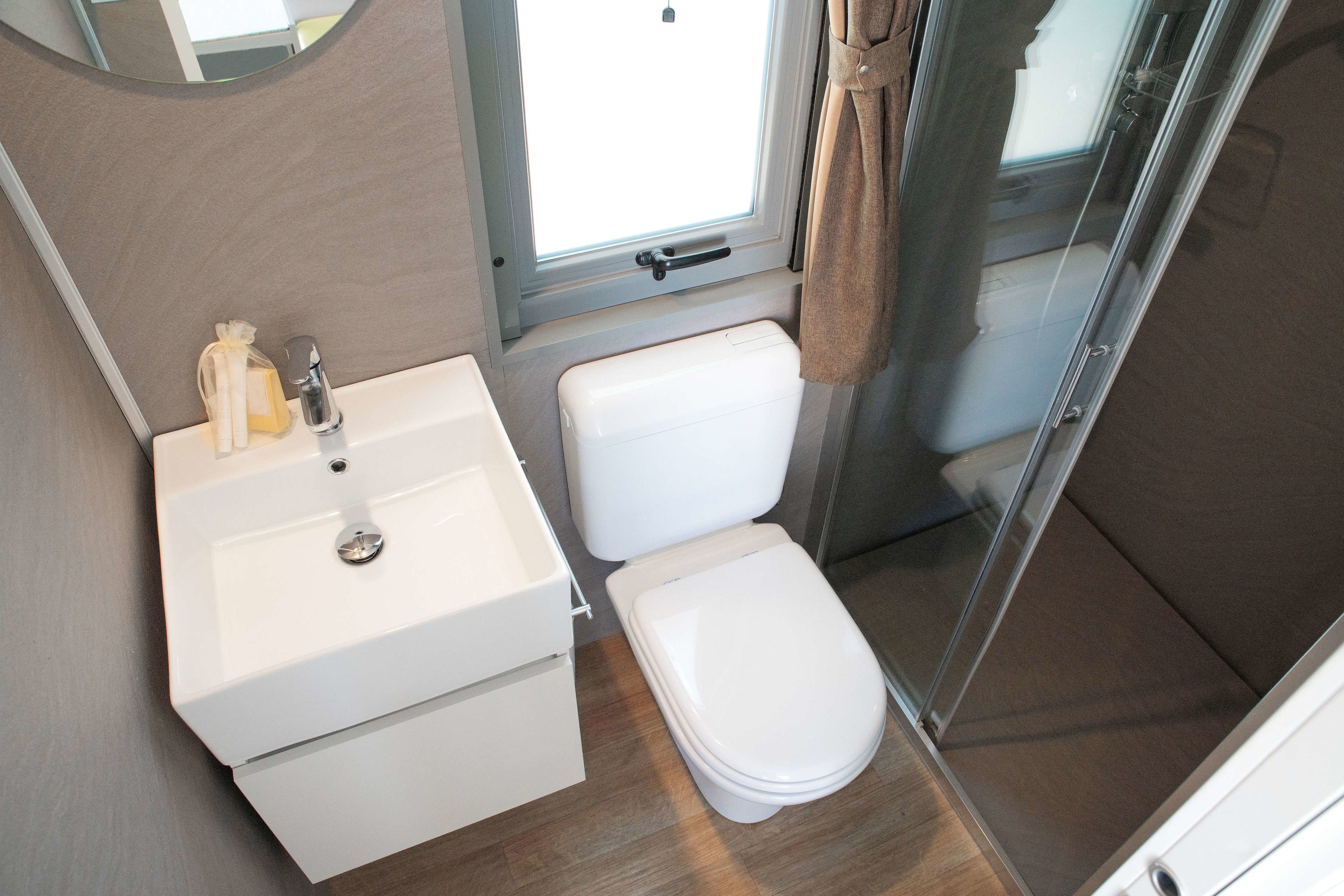 A compact bathroom with a white sink, toilet, and shower area.
