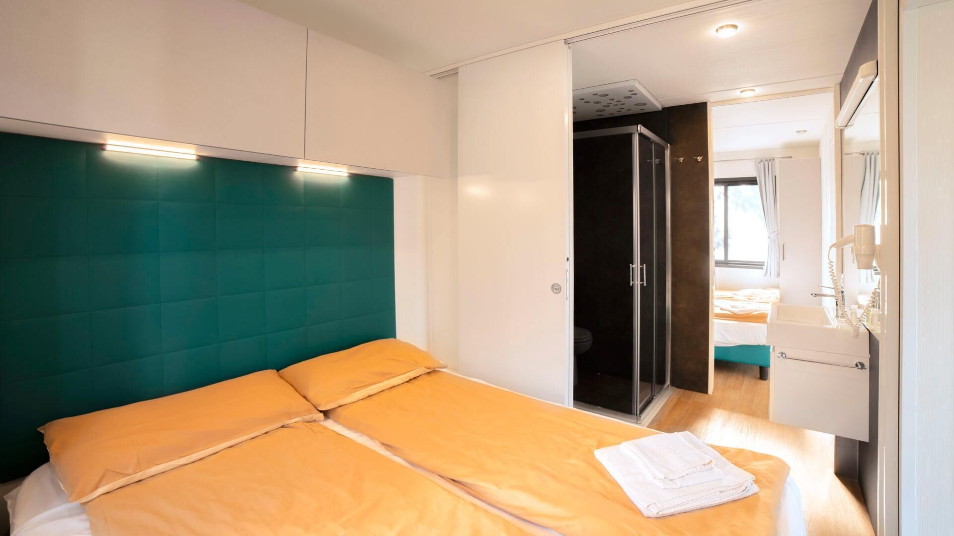 A modern hotel room with a large bed, a walk-in closet, and a bathroom with a shower and toilet.