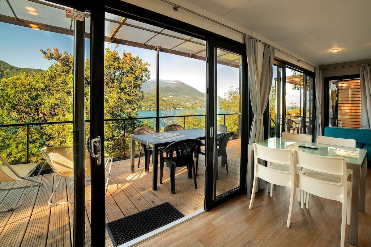 A modern room with a glass door leading to a balcony overlooking a scenic view.