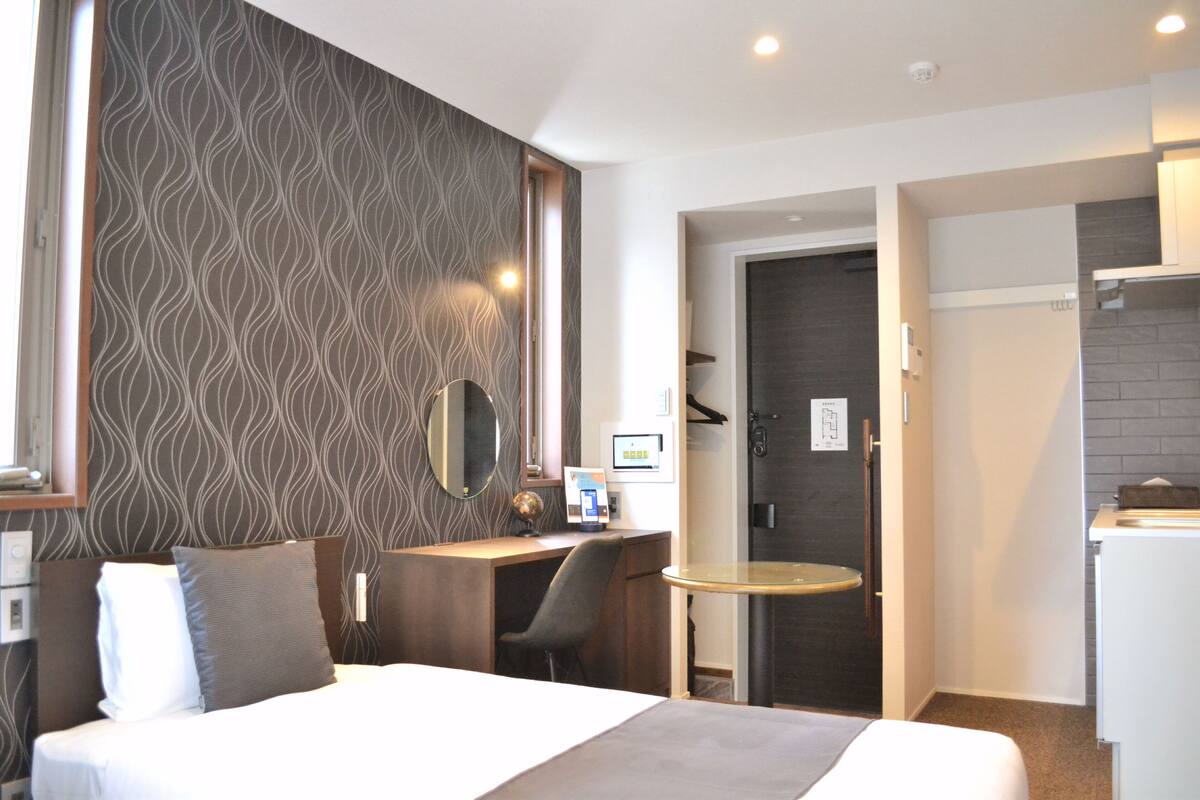 A hotel room with a bed, desk, chair, and a small round table.