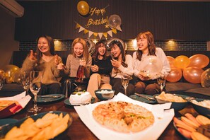 A group of people seated at a table with food and drinks, a 'Happy Birthday' banner, and balloons in a restaurant setting. - Grand Base Hakata Kukodori (Fukuoka)