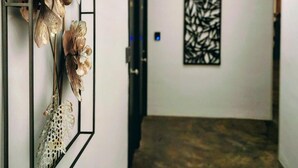 A hallway with a modern design, featuring a decorative wall panel with metallic flowers and a geometric wall art piece. - White Village Boutique, Benalmádena - Self Check-in (Benalmádena)