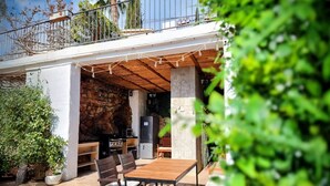 An outdoor patio with a wooden table and chairs, a stone wall, and a balcony with railings. - White Village Boutique, Benalmádena - Self Check-in (Benalmádena)
