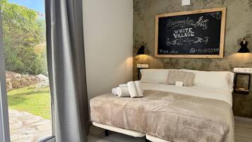 Un dormitorio con cama, vistas al exterior, un cartel de pizarra y una lámpara.