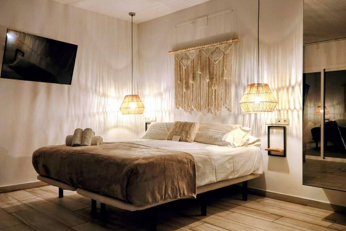 A modern bedroom with a large bed, two bedside lamps, and a wall-mounted TV.