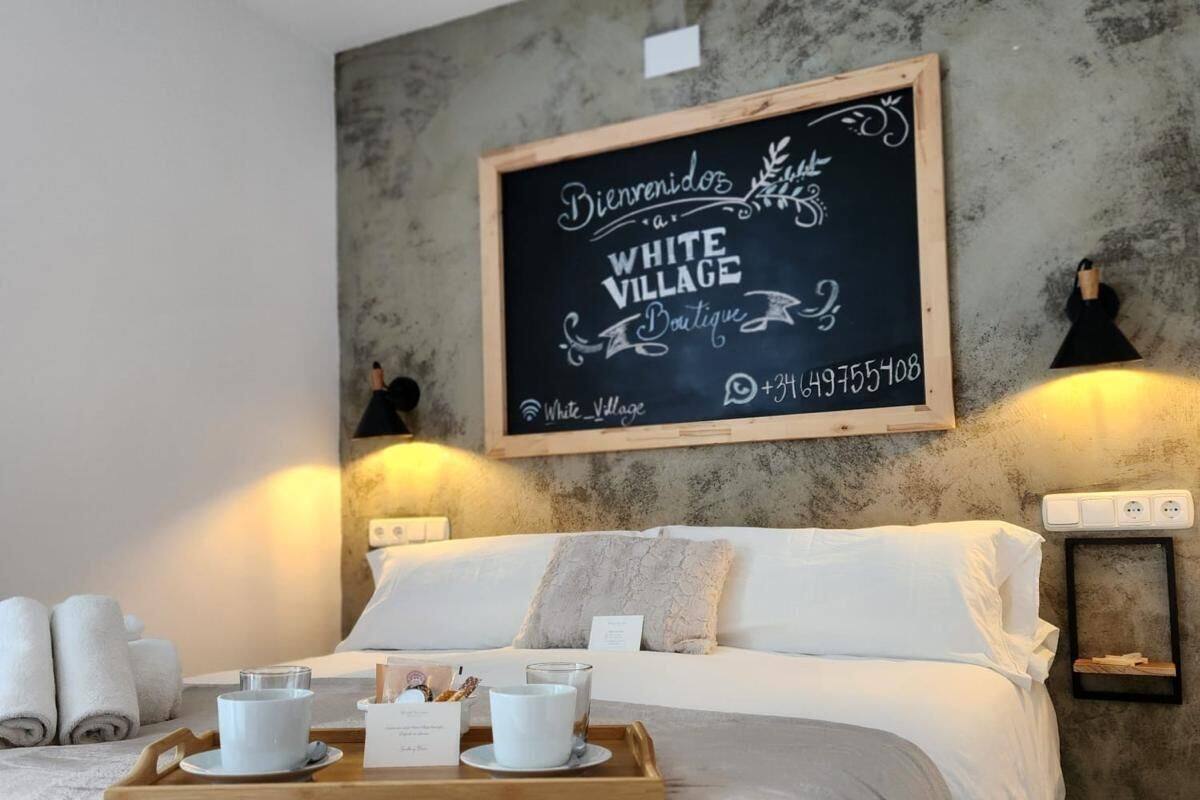 A hotel room with a bed, a tray with breakfast items, a chalkboard sign, and two wall-mounted lamps.