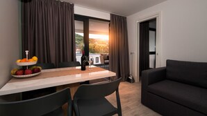 A dining area with a table set for two, a bowl of fruit, and a bottle of wine. - Mobile Homes Camping Plitvice (Plitvicka Jezera)