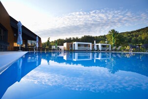 Una piscina al aire libre, sombrillas, sillones reclinables de piscina