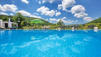 Una piscina al aire libre, sombrillas, sillones reclinables de piscina