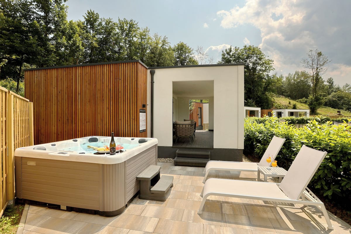 Ein Whirlpool mit Holzterrasse, eine kleine Sitzgelegenheit mit Stühlen und ein Holzzaun.
