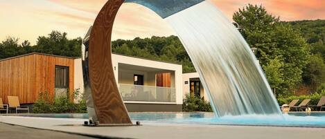 Een buitenzwembad, parasols bij het zwembad en ligstoelen