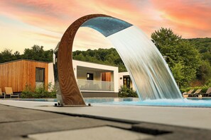 A modern building with a wooden facade and a pool area with lounge chairs. - Mobile Homes Camping Plitvice (Plitvicka Jezera)