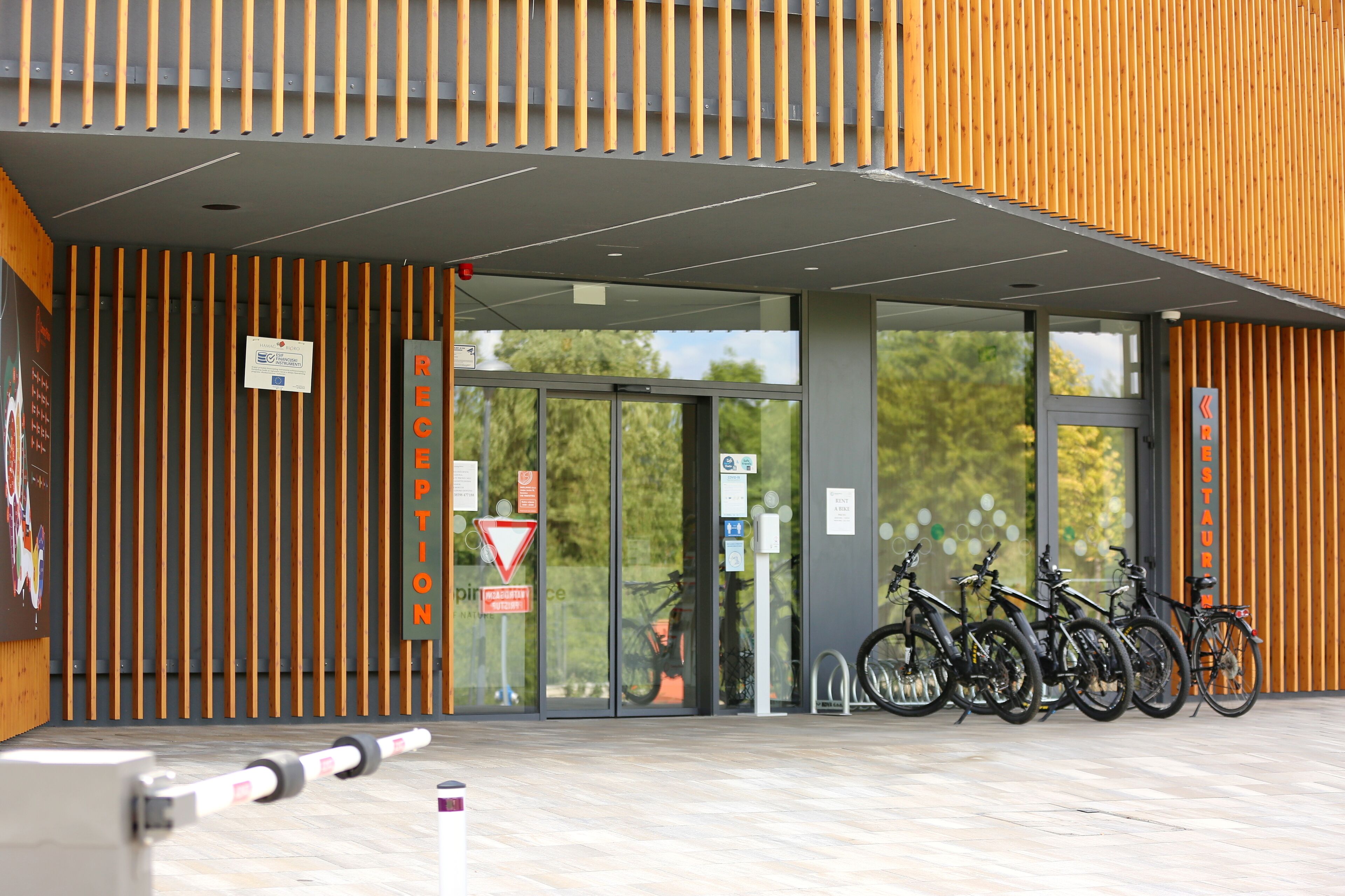 Une entrée moderne, avec un revêtement en lambris de bois, des portes en verre et un espace réservé au stationnement des vélos.