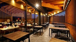 A restaurant with wooden tables and chairs, large windows, and a warm interior lighting. - Mobile Homes Camping Plitvice (Plitvicka Jezera)