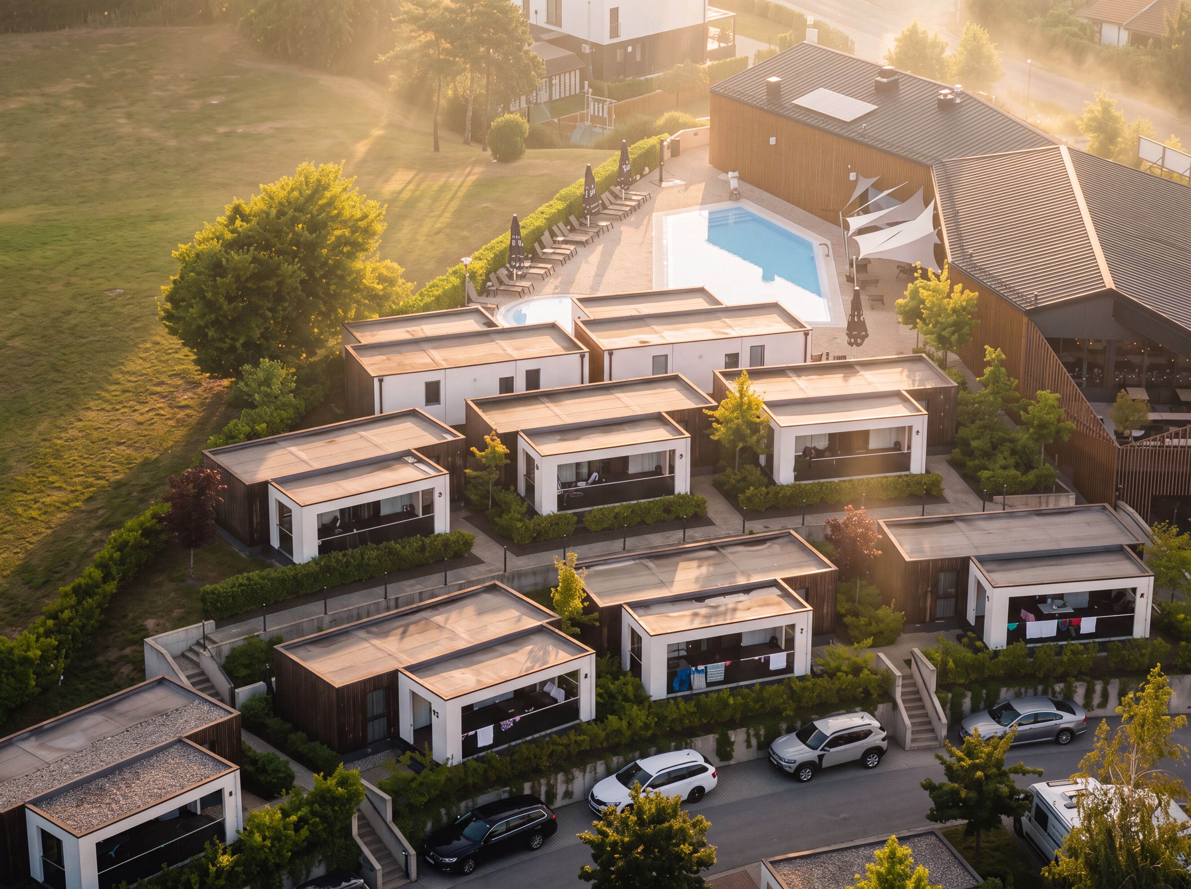 A modern residential complex with multiple detached houses, a swimming pool, and a parking area.