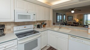 Una cocina moderna con armarios blancos, microondas integrado, estufa y lavaplatos.