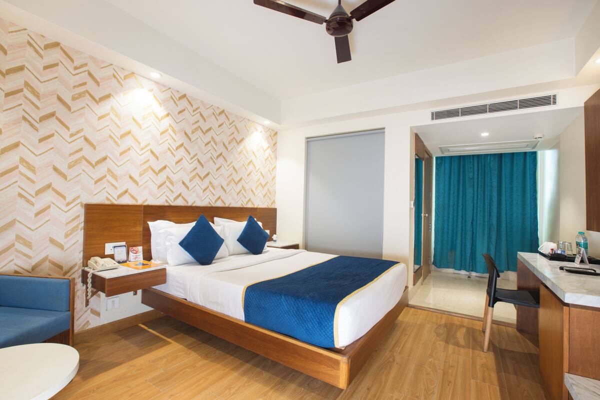 Ein Hotelzimmer mit einem hölzernen Bett, einem Schreibtisch, einem Sessel und einem Badezimmer mit Dusche und Toilette.