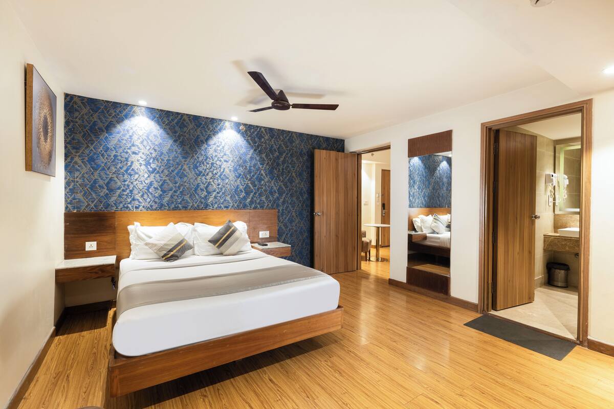 Ein Schlafzimmer mit einem hölzernen Bett, einem Deckenventilator und einem durch eine offene Tür einsehbaren Badezimmer.