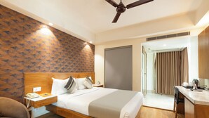 Habitación de hotel con una cama de madera, un escritorio, una silla, un teléfono y una puerta que da a un baño.