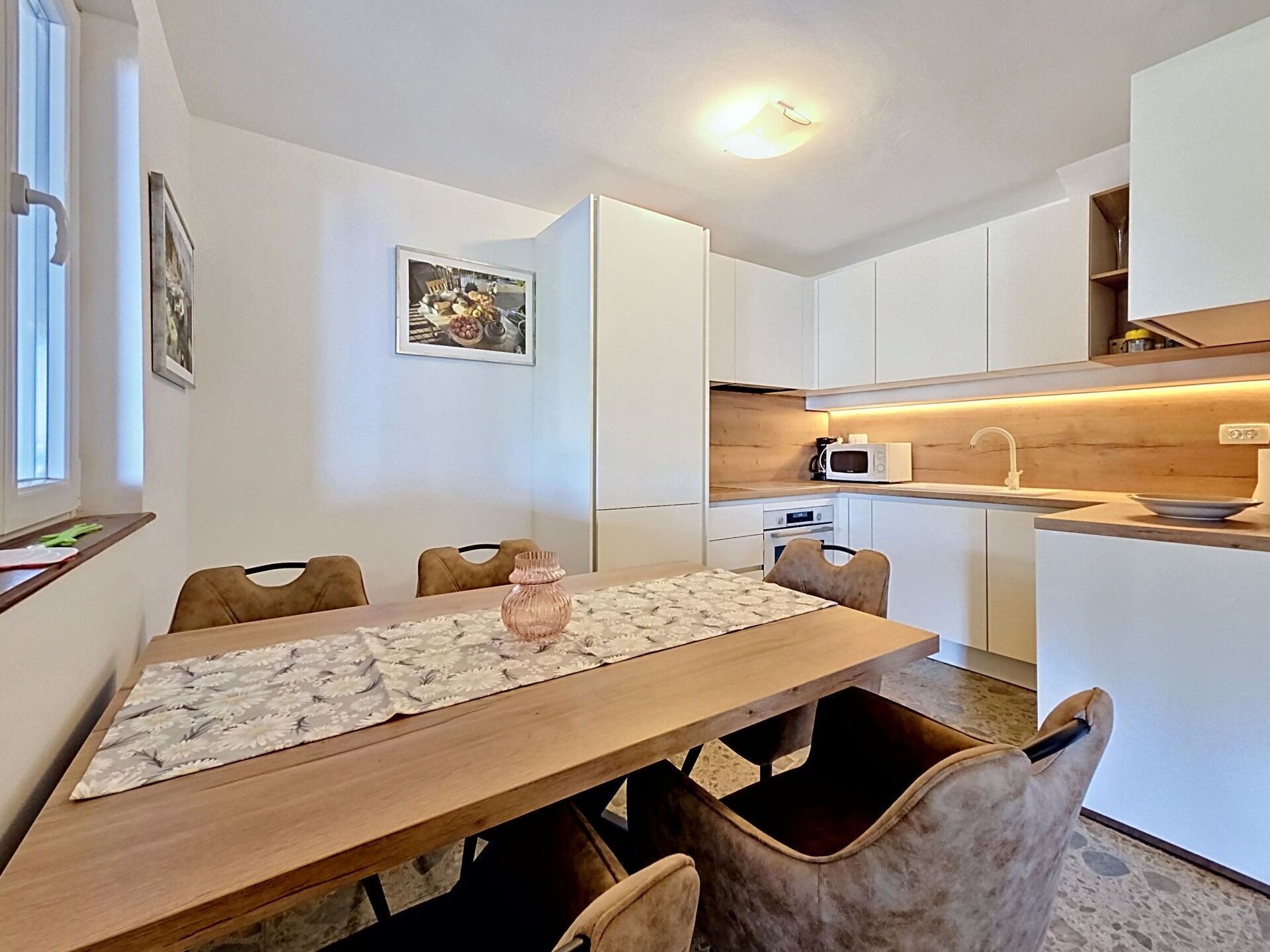 Une cuisine moderne avec des armoires blanches, un plan de travail en bois et un four à micro-ondes encastré.
