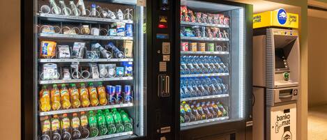 Two beverage vending machines with a bank ATM next to them.