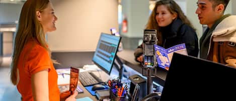 Mostrador de recepción con computadora, teléfono y atril para mapas.