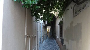 A narrow alleyway with cobblestone pavement, a metal door, and a wall with graffiti. - "Casetta del Borghetto" - "In the Heart of the Borghetto" Near the sea and Rome. (Nettuno)
