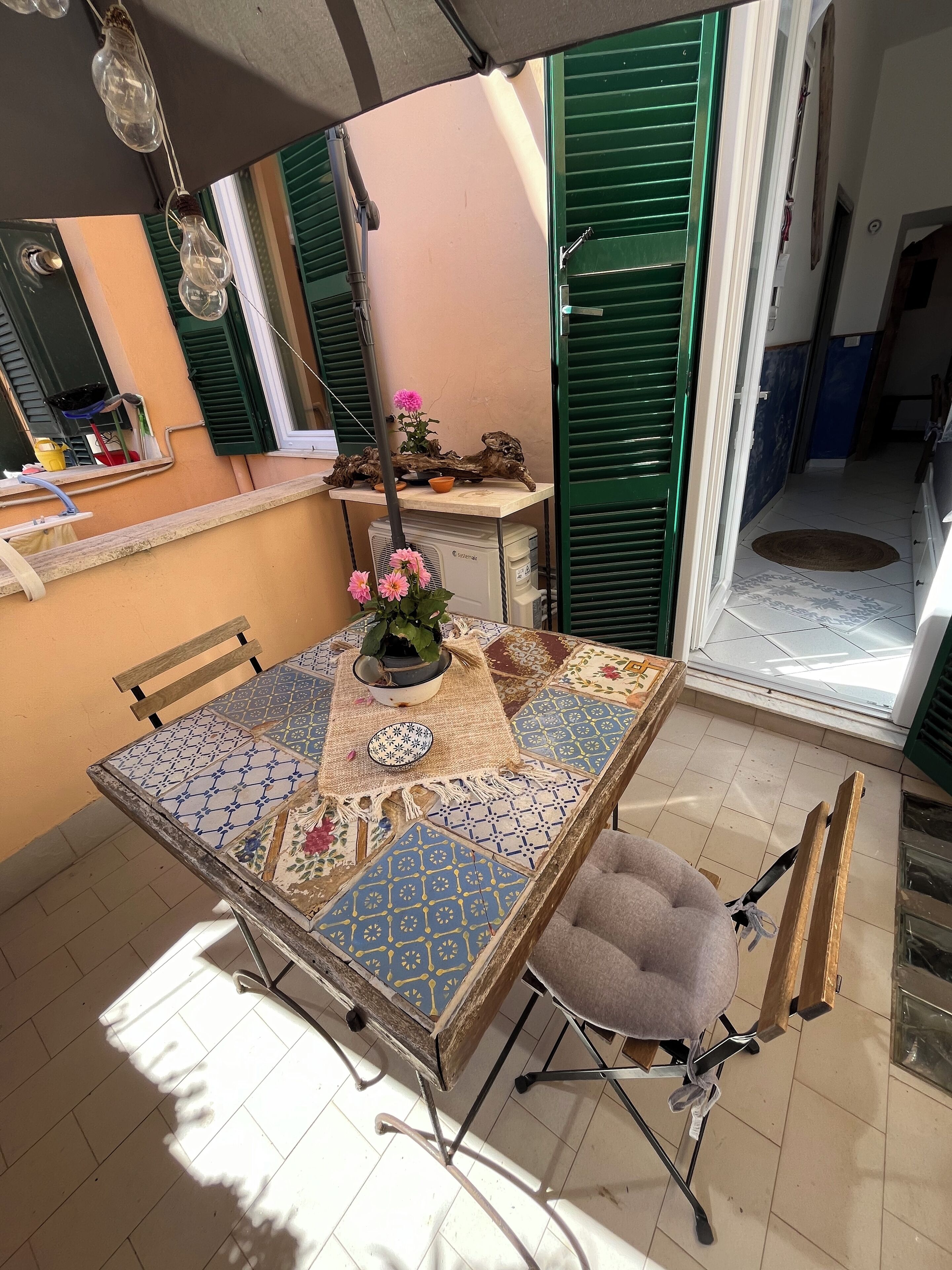 A dining area with a tiled table, chairs, and a potted plant.