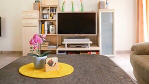 Un salon équipé d’un téléviseur à écran plat, de bibliothèques, d’une table basse agrémentée d’objets décoratifs et d’un canapé.