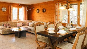 Un coin repas accueillant et bien éclairé, avec une table en bois dressée pour quatre personnes, entourée de chaises assorties.
