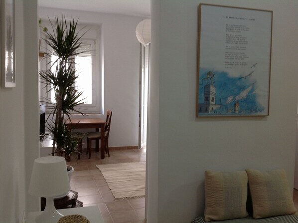 A dining area with a table and chairs, a potted plant, and a framed artwork on the wall.
