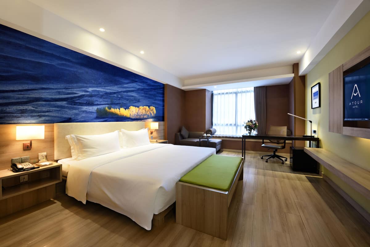 Quarto de hotel moderno com uma cama grande, uma escrivaninha e uma televisão.