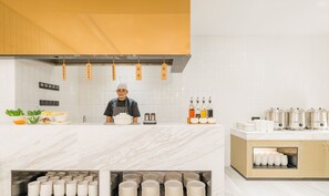 A modern kitchen with a chef, a marble countertop, and various food items. - Atour Hotel New International Expo Center Longyang Road Shanghai (Shanghai)