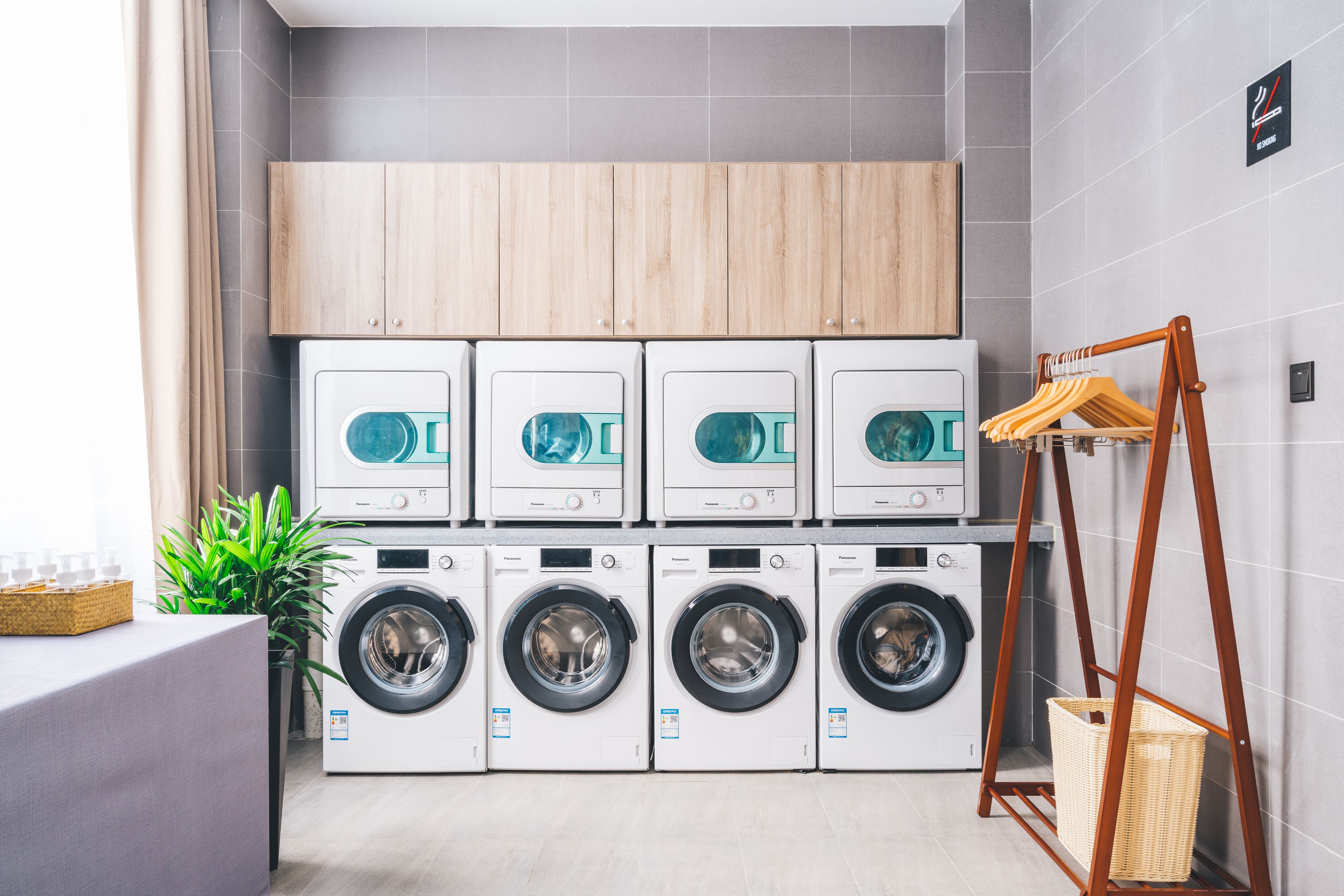 A laundry area with multiple washing machines and a wooden cabinet above them.