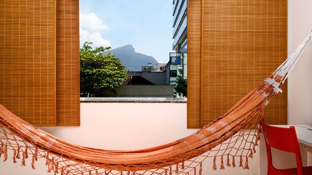 A hammock in a room with a view of a mountain and a building. - Omar do Rio - VP303 (Rio de Janeiro)